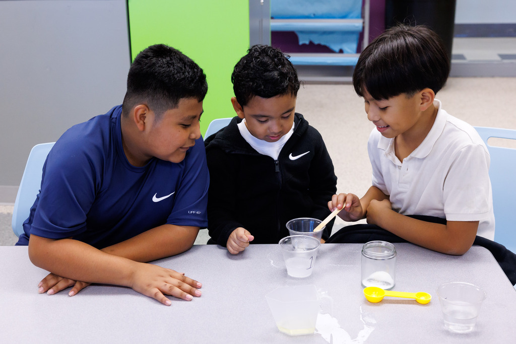 Three students work on a science experiment about dissolving soutions.