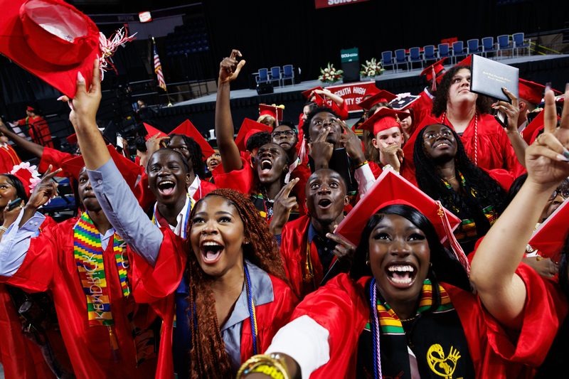 Students in graduation gowns cheering