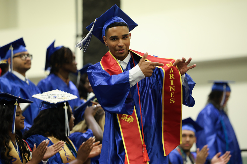 A Worcester Technical High School graduate points to their United States Marine Corps graduation stole while walking across the stage during the school's Class of 2026 commencement ceremony at the DCU Center.