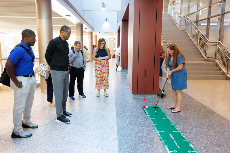 Staff make putts in a mini-golf course as part of a professional development activity.