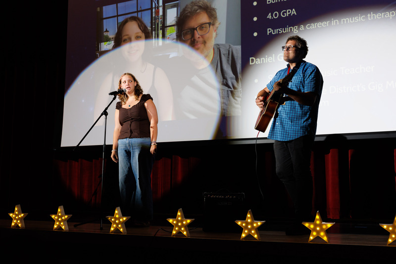 A student and her father perform a song during an event.