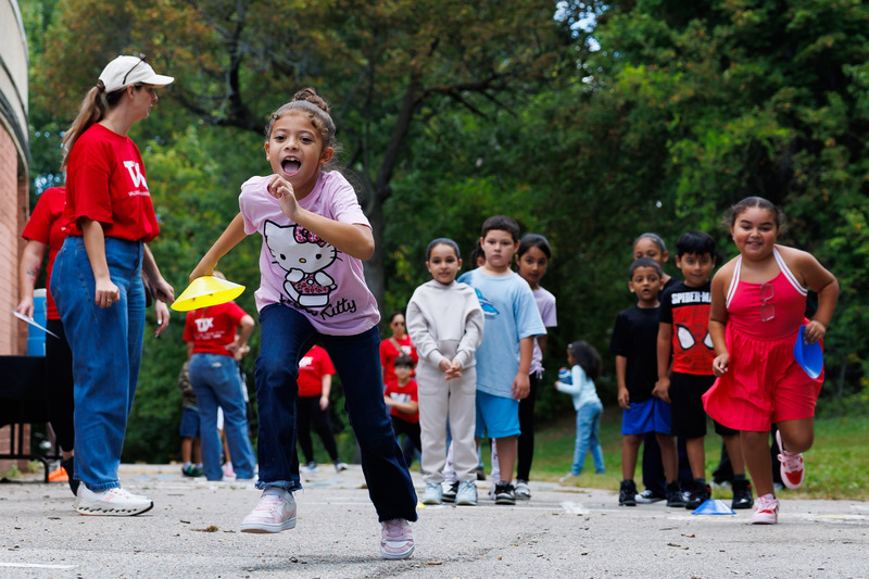A student runs while outdoors with another closely behind.