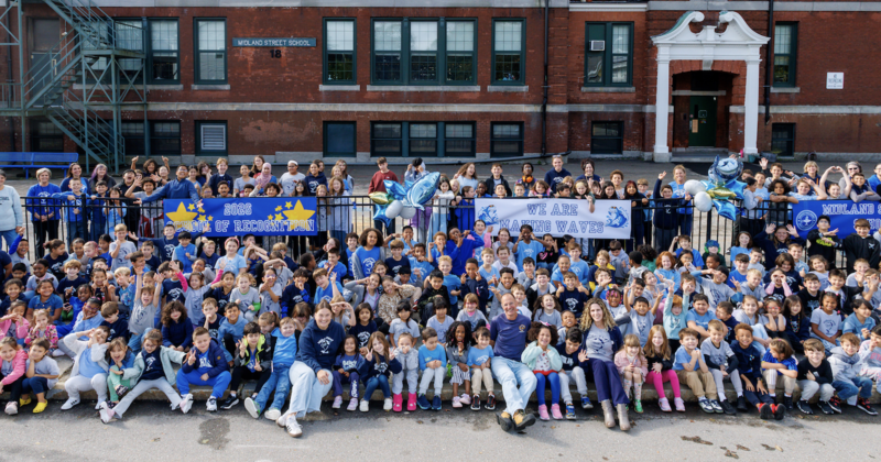 A large group of students outside a school and a banner that says "2026 School of Recognition"