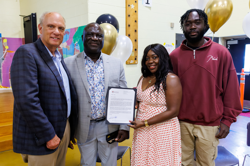 Mayor Joseph M. Petty presents a Key to the City to the family of New Orleans Saints cornerback and Worcester Public Schools alumnus Isaac Yiadom during a backpack donation event at Chandler Elementary Community School.