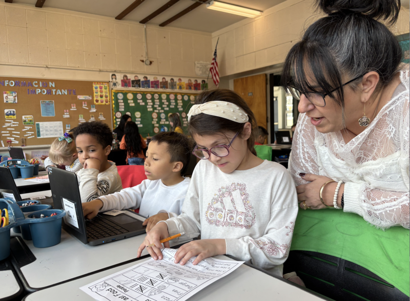 A student looking at a worksheet while the principal looks on