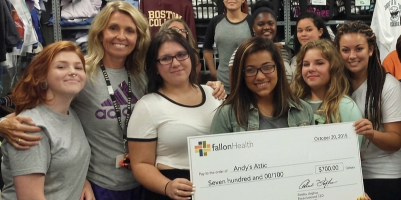 A group of smiling women pose for a photo, holding a large check for $500.00 made out to Andy's Attic.