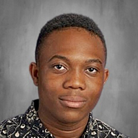 A young Black male with short, dark hair and a patterned shirt smiles gently.