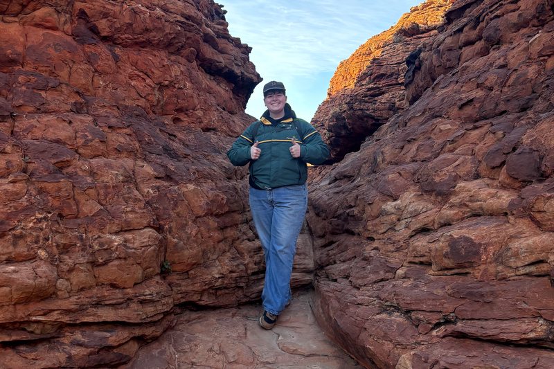 Jupiter Montalvo stands between two red rock boulders during a backpacking trip.
