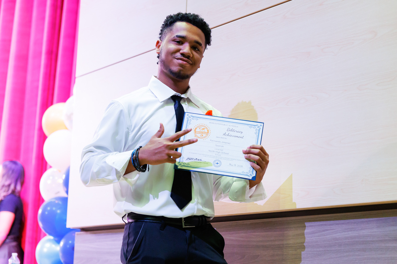 A student points at their certificate following a celebration ceremony.