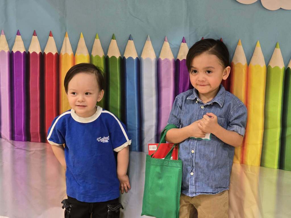 2 boys standing in front of a pencil poster