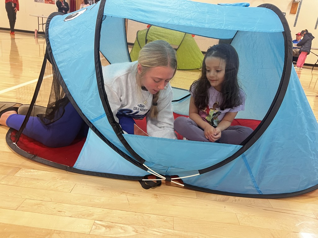 2 girls reading in a tent