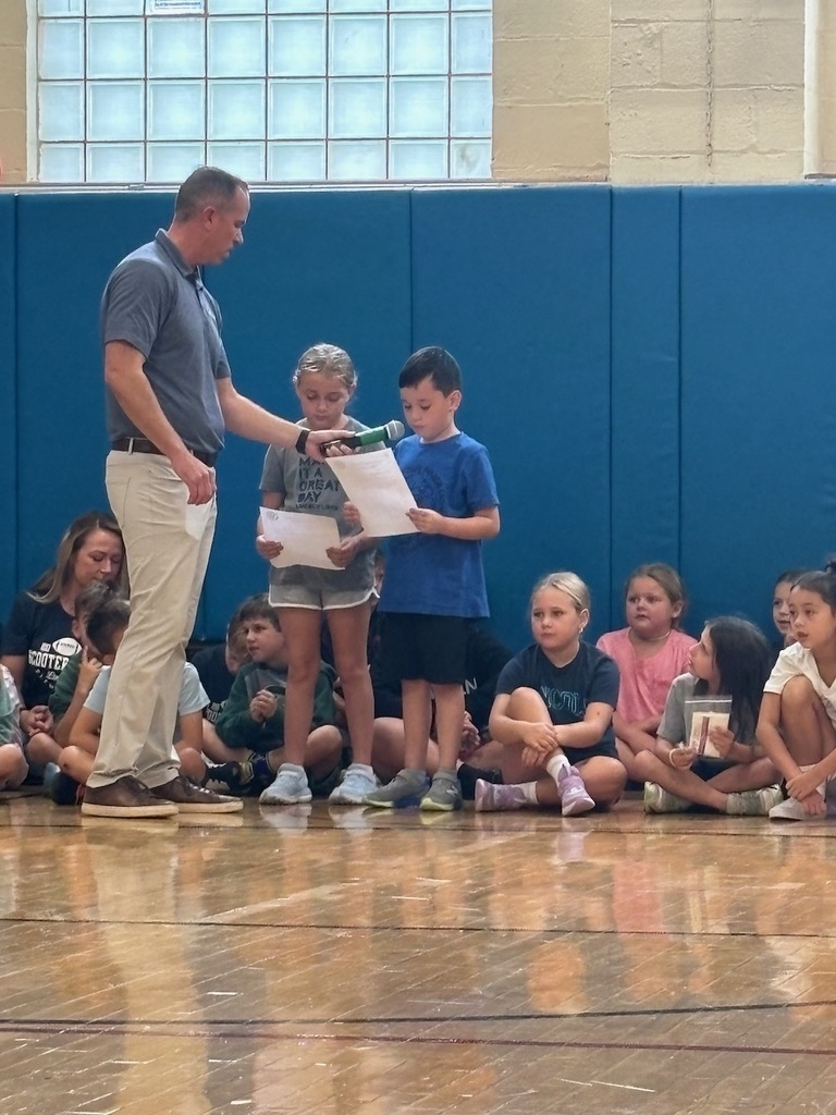 Two students talking into microphone sharing their class's hopes and dreams for the school year.