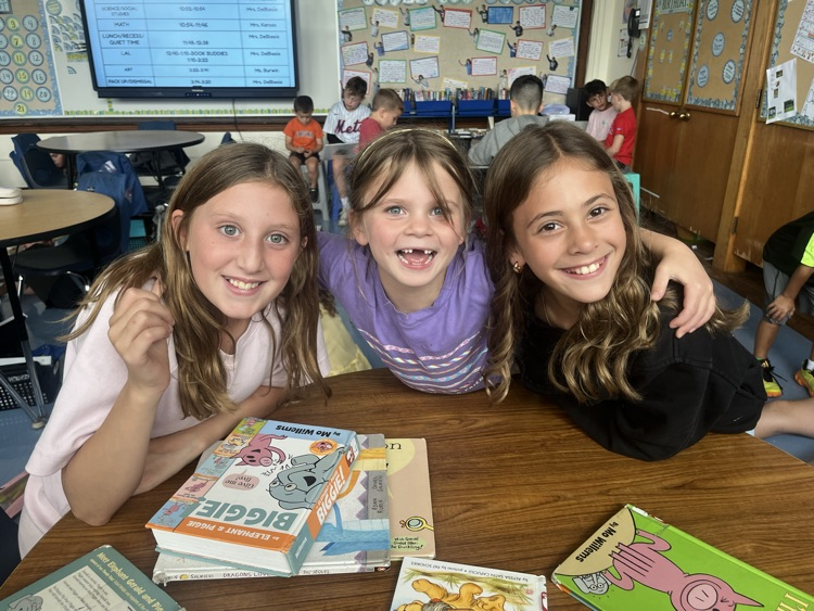 three students smiling and holding books