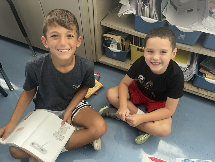 two students smiling and holding books