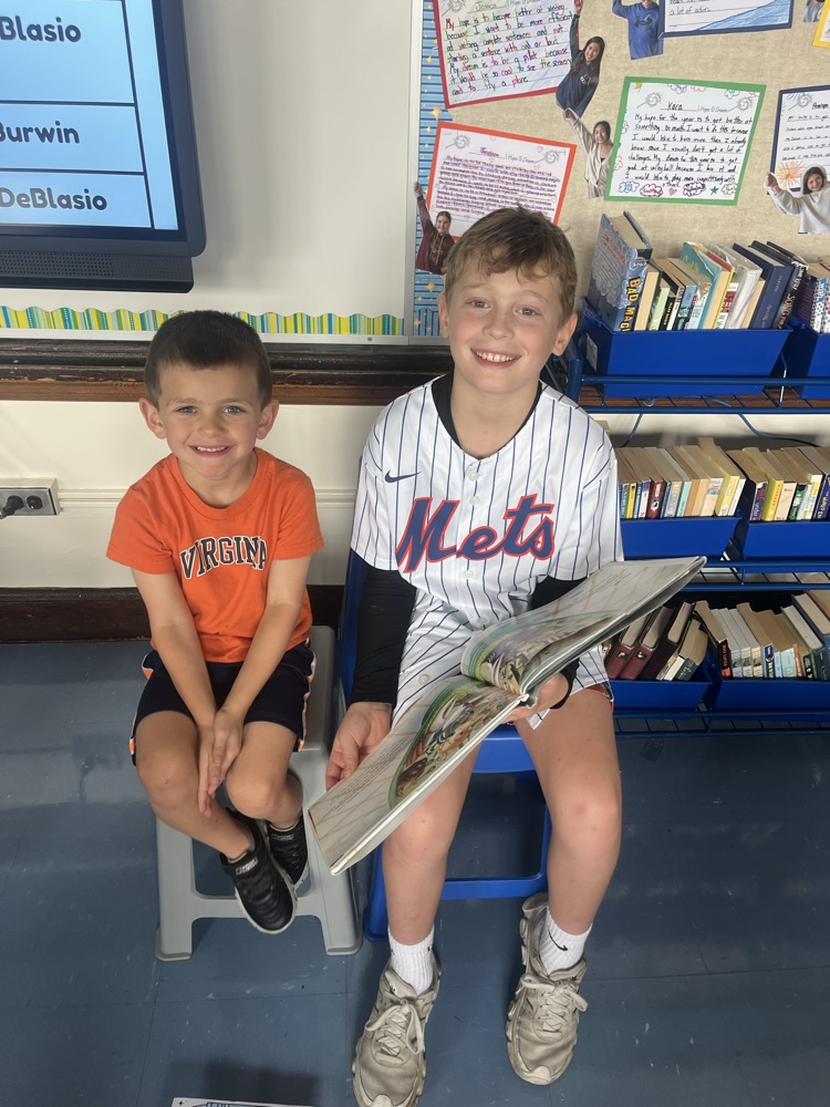two students smiling and holding books