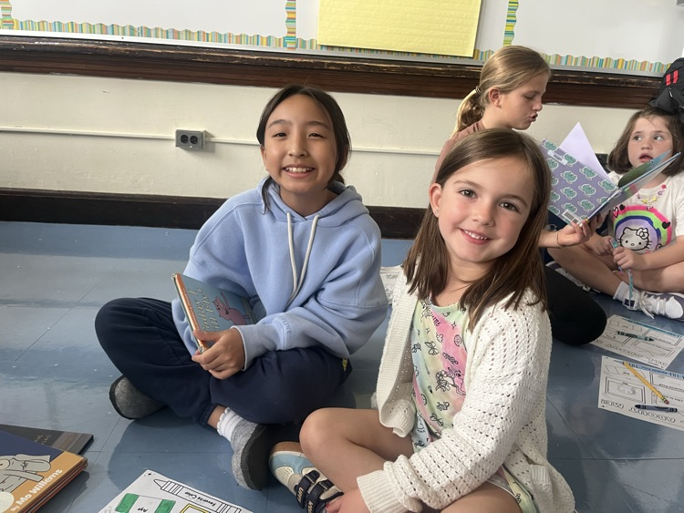 two students smiling and holding books