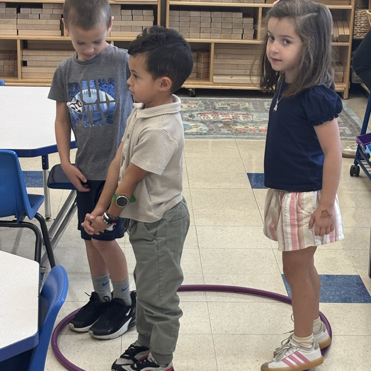 children standing in a hula hoop