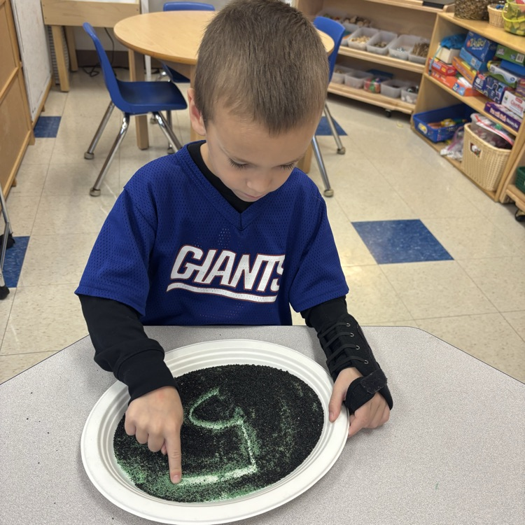 boy writing in a sand tray