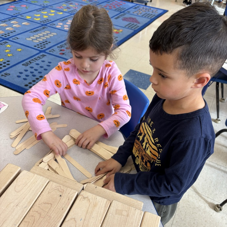 children working to build a house made of tongue depressors