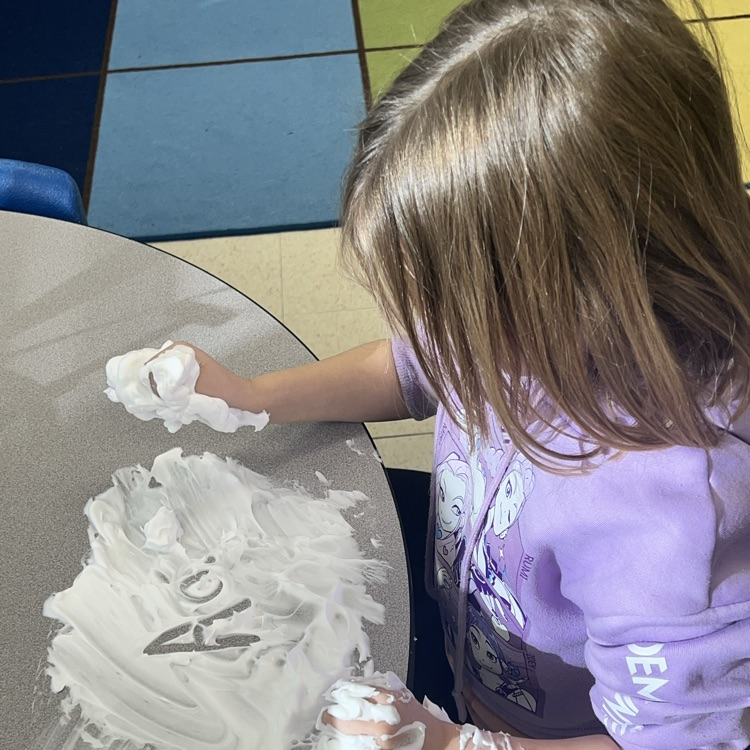 KRO practices letter formation and letter sounds by tracing in shaving cream.