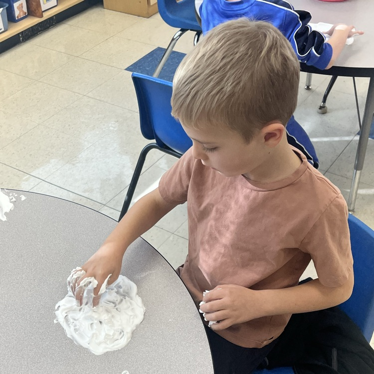 KRO practices letter formation and letter sounds by tracing in shaving cream.