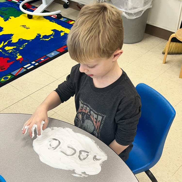 KRO practices letter formation and letter sounds by tracing in shaving cream.