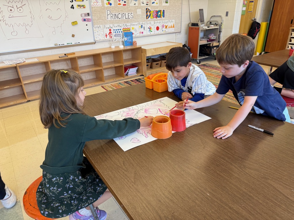 Three students painting together in the art room.