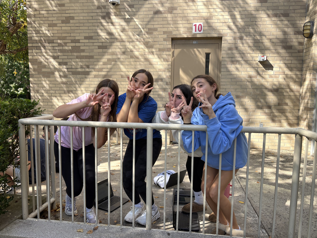 4 students pose with peace signs and silly faces for a photo