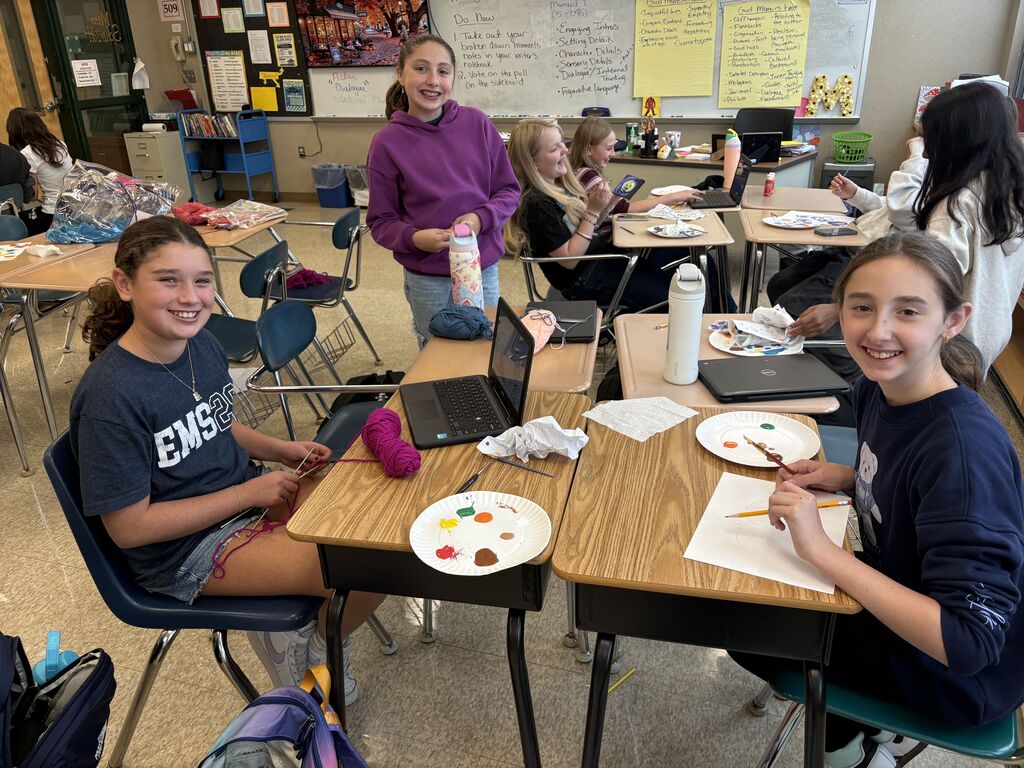 3 students smile for the camera while doing a variety of crafts