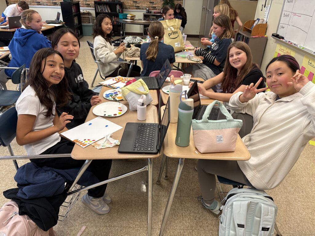 A large group of students smile for a photo while crafting with each other.