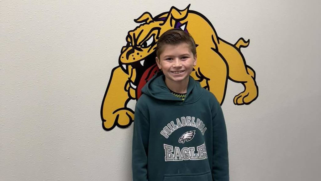 A student at Wylie Intermediate East smiles while wearing a Philadelphia Eagles hoodie, standing in front of a bulldog mascot mural.