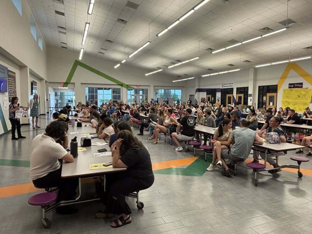 Parents and students gathered in a school cafeteria for an evening meeting or presentation.