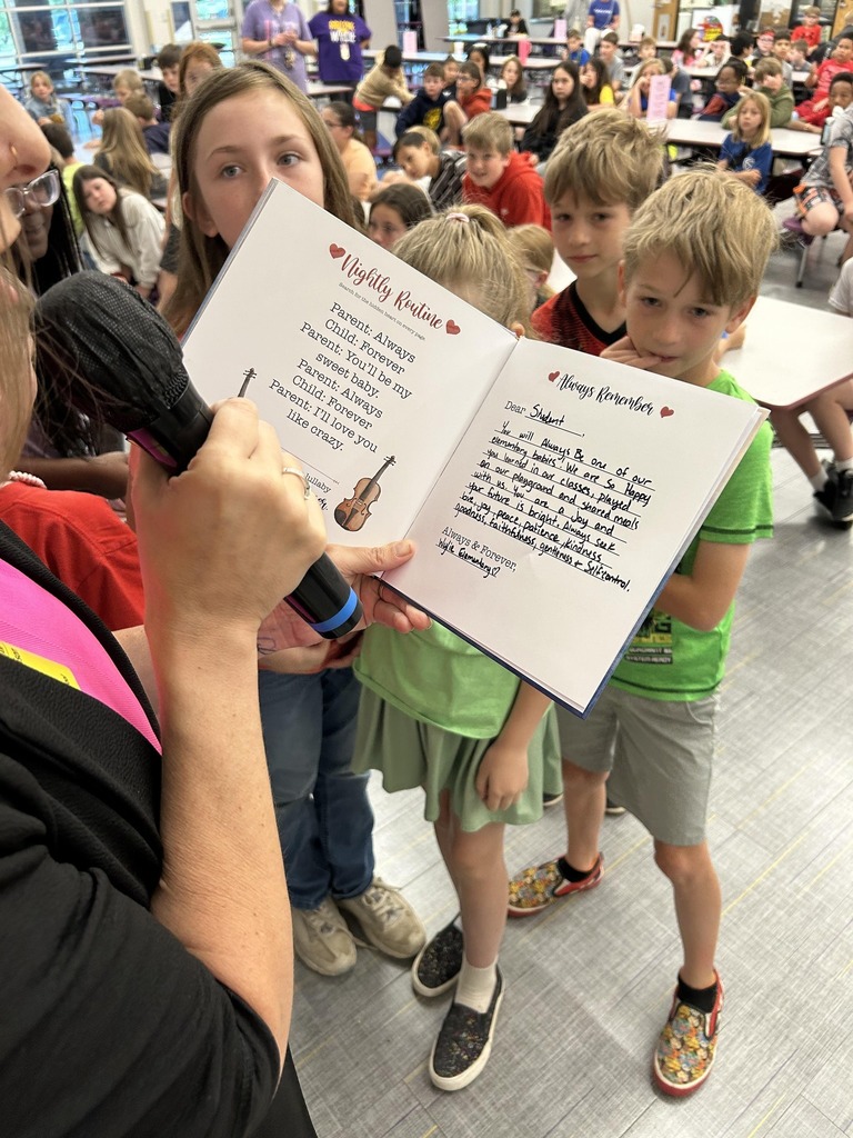Close-up of a book being read aloud to students, with children gathered around the reader.