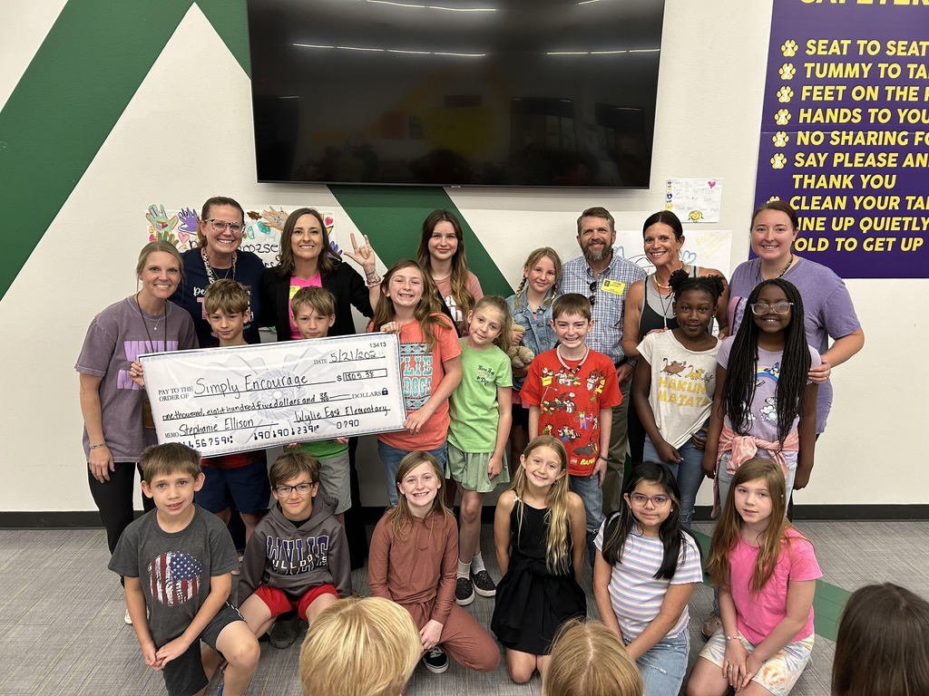 Students and staff pose with Stephanie Ellison and a large donation check to Simply Encourage.