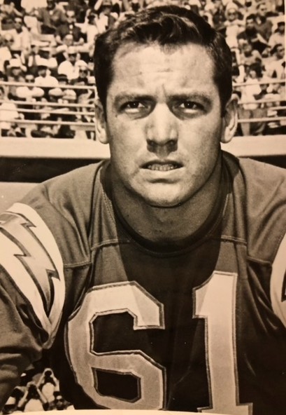 Black-and-white photo of Ernie Park in a football uniform with the number 61, looking directly at the camera while on the field, with a stadium crowd visible in the background.