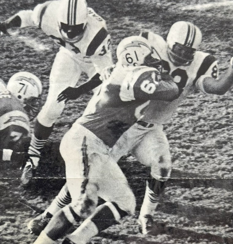 Black-and-white action photo of Ernie Park, wearing number 61, blocking an opposing player during a football game while other players engage around him on the field.