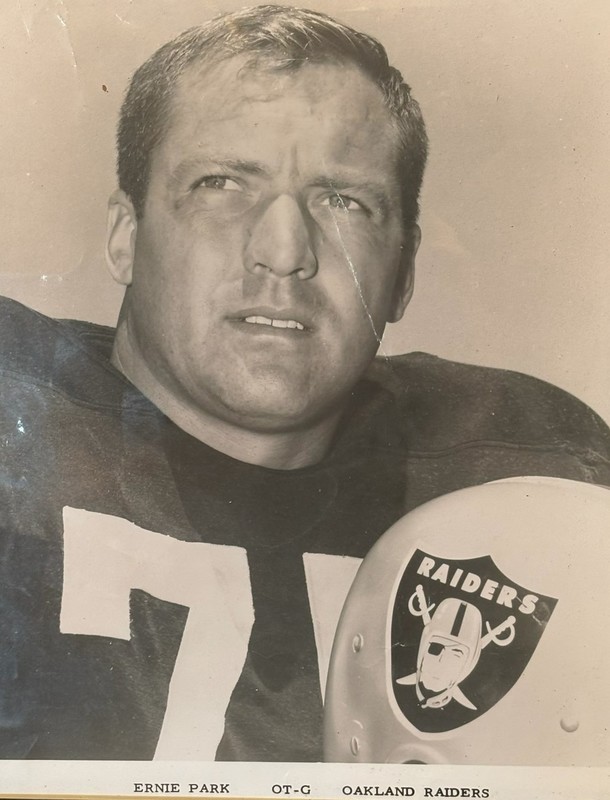Black-and-white portrait of Ernie Park wearing a football uniform with the number 74, holding a helmet with the Oakland Raiders logo, with printed text below identifying him as “Ernie Park, OT-G, Oakland Raiders.”