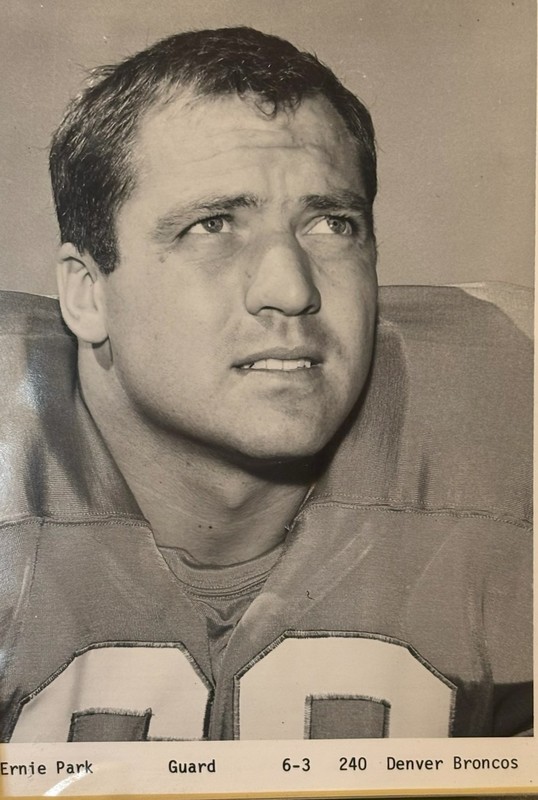 Black-and-white portrait of Ernie Park in a Denver Broncos football uniform, looking slightly upward, with printed text below listing his name, position as guard, height and weight, and team.