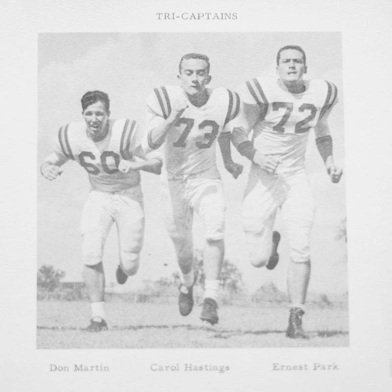 Black-and-white yearbook photo labeled โTri-Captainsโ showing three football playersโDon Martin, Carol Hastings, and Ernest Parkโrunning forward in uniform on a field.