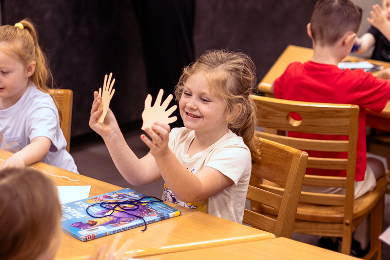 Kindergarten students participate in a classroom activity at tables in the Wylie East Elementary library while staff members assist around the room.