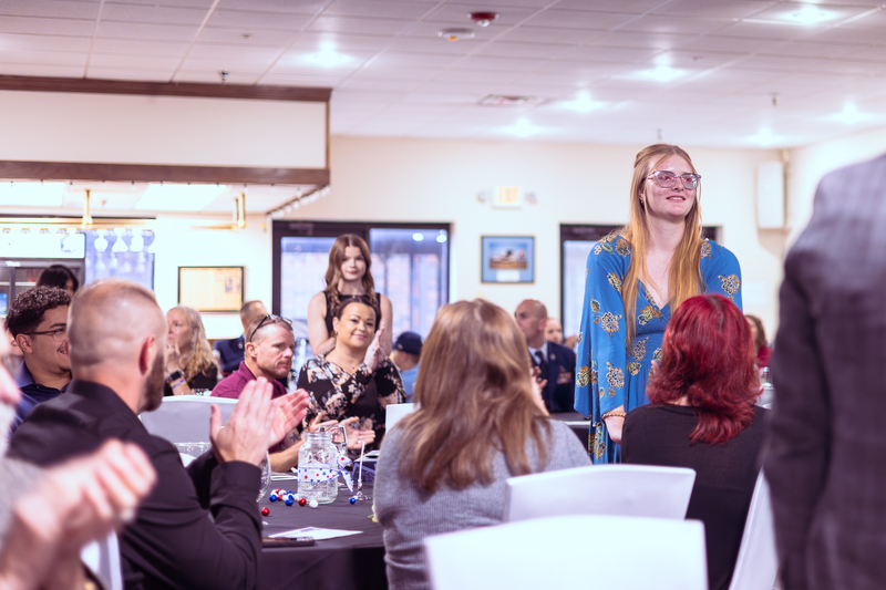 Student seated at a table speaking with others during the Military Signing Day event.