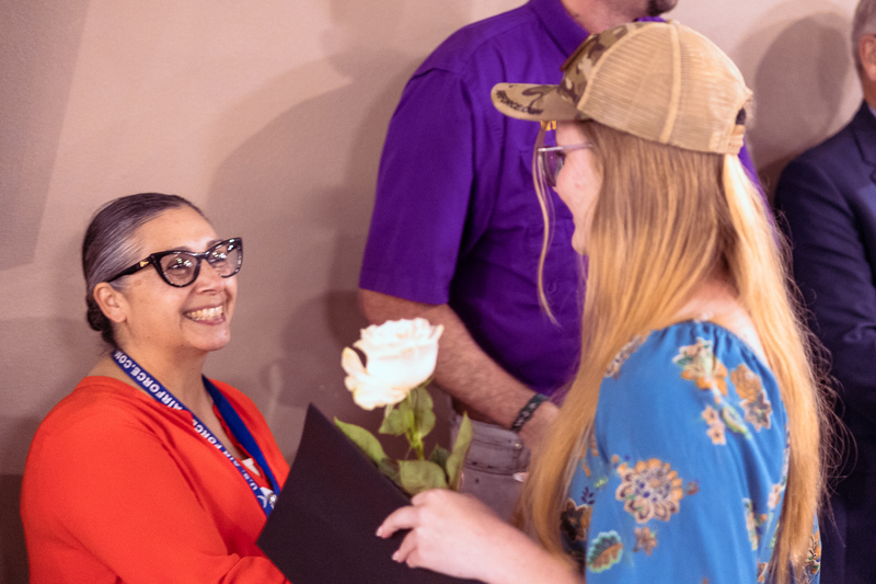 Staff member in a purple Wylie shirt congratulating a student with a handshake.