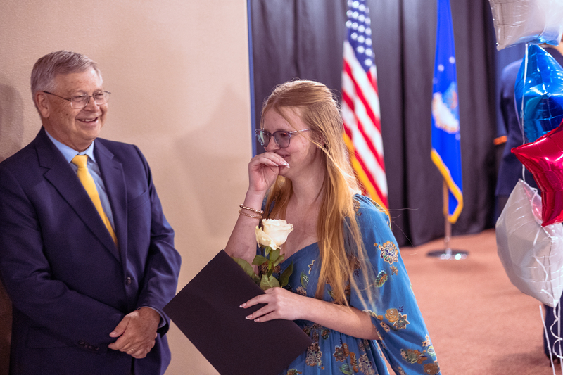 Close-up of a student smiling and talking with a staff member during the ceremony.
