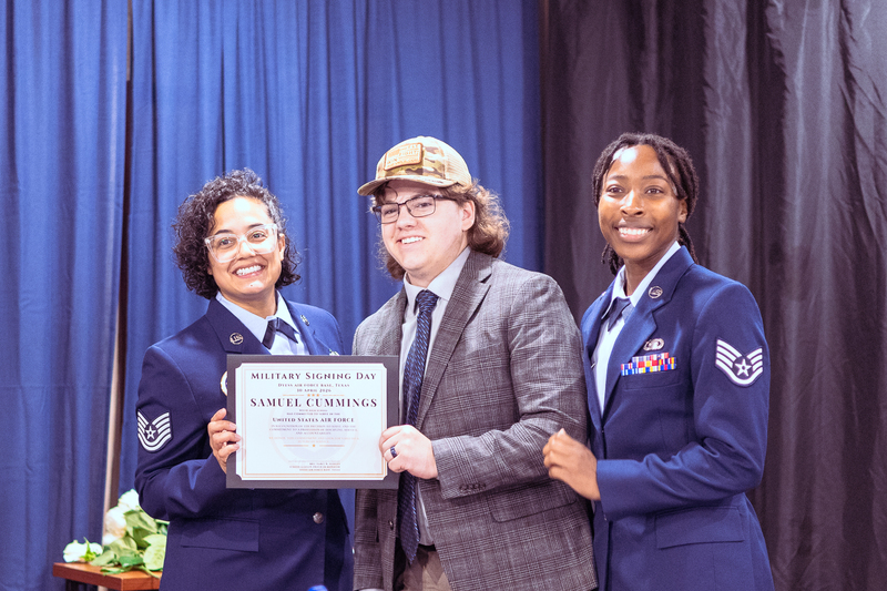 Student holding a certificate while standing with a staff member and smiling for a photo.