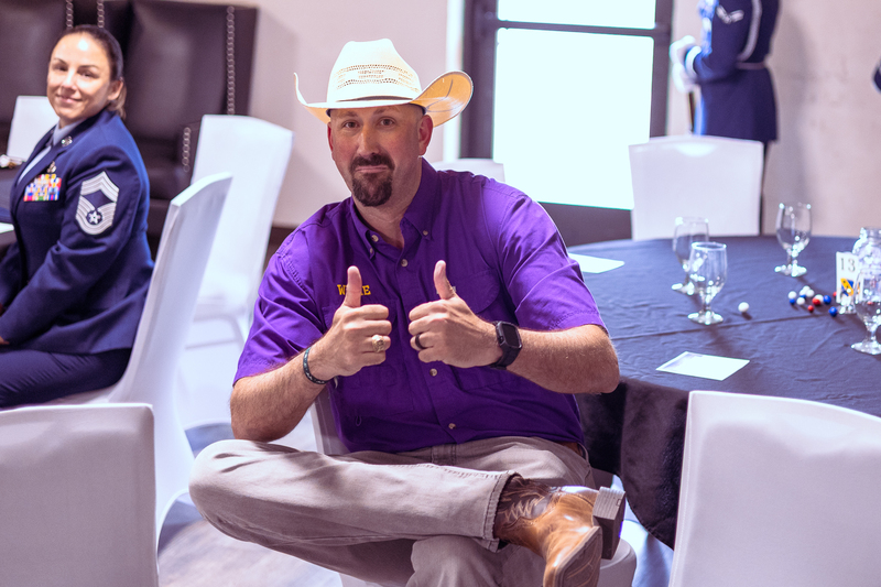 Wylie staff member in a purple shirt and cowboy hat seated and speaking during the event.