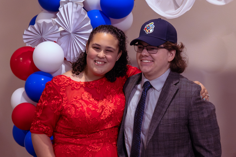 Two guests smiling together for a photo with balloons in the background.