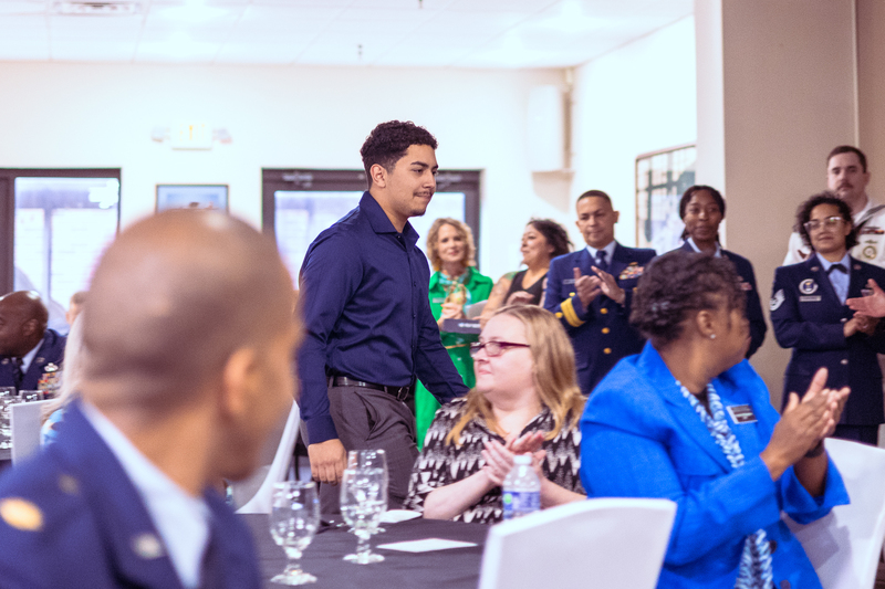 Student walking with a staff member while seated at a decorated table during the event.