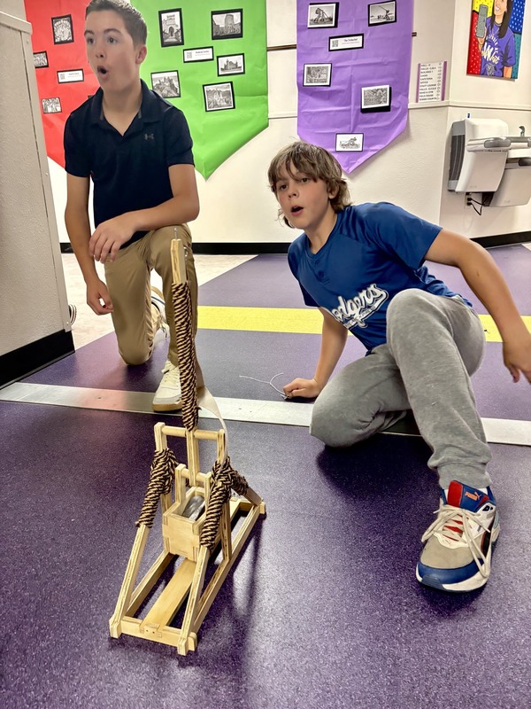 3. Ryder Johnston and Barrett Hyde watch expressly as Hyde's trebuchet launches weaponry at a castle made of Legos.