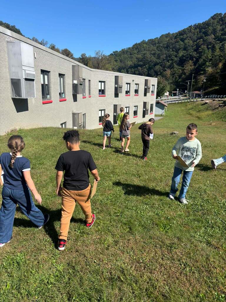 Students search for leaves on the school front lawn.