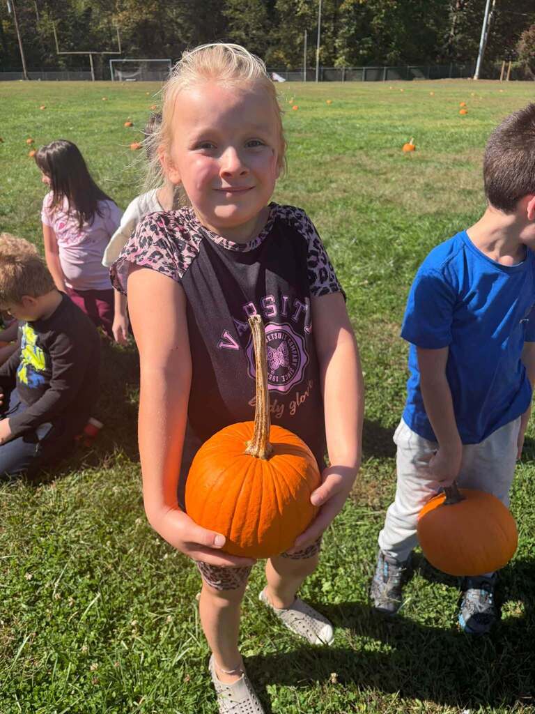 A Berlin Student holding one of the small pumkins scattered on the old Oceana High School Football Field.